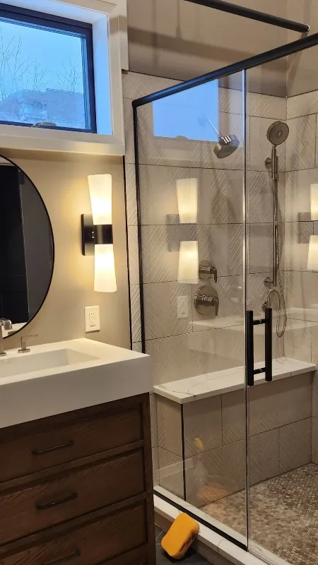 Remodeled bathroom with glass walk-in shower, wood vanity and slate tile floor