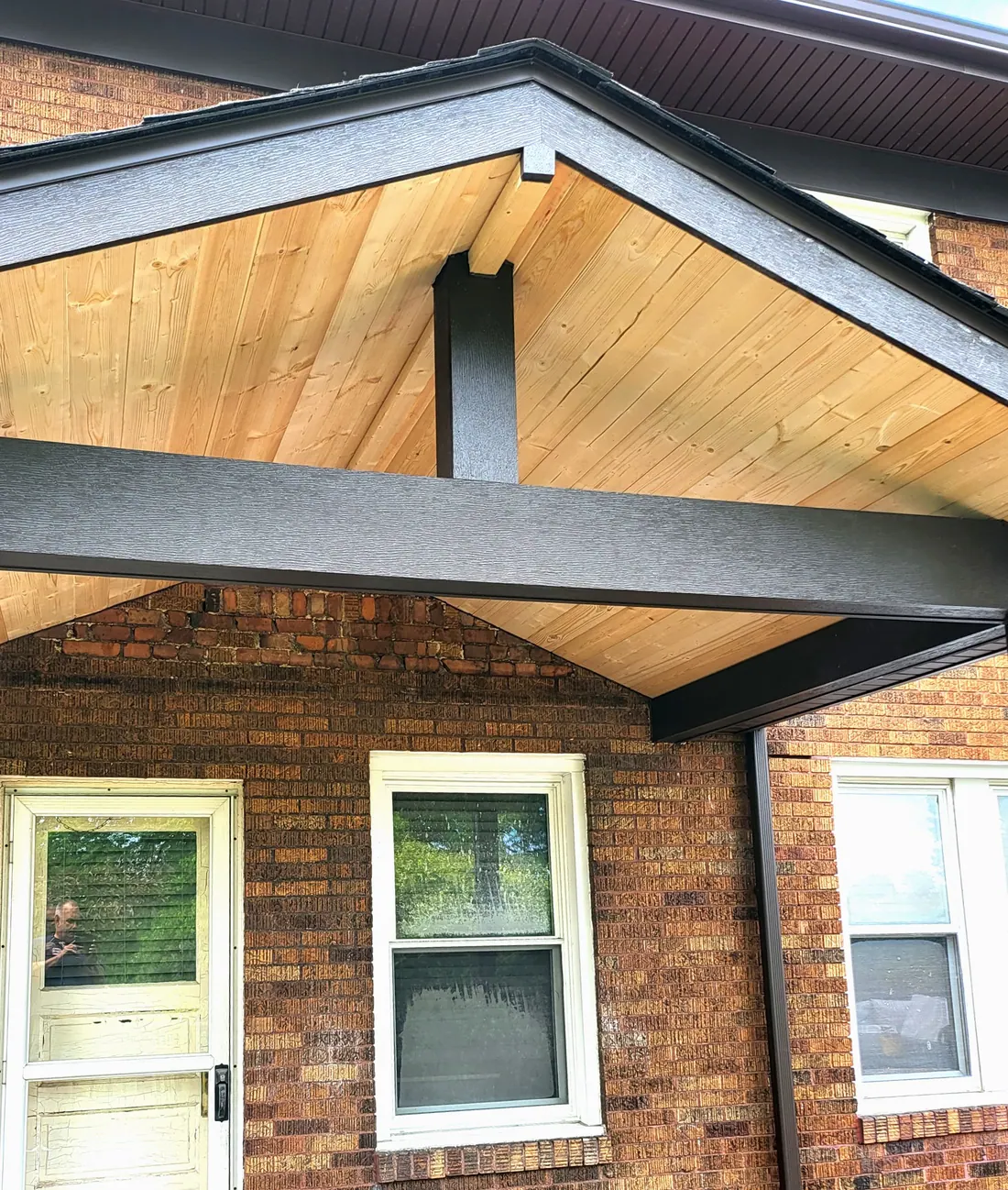 New porch roof with stained timber gable built over a brick home entry